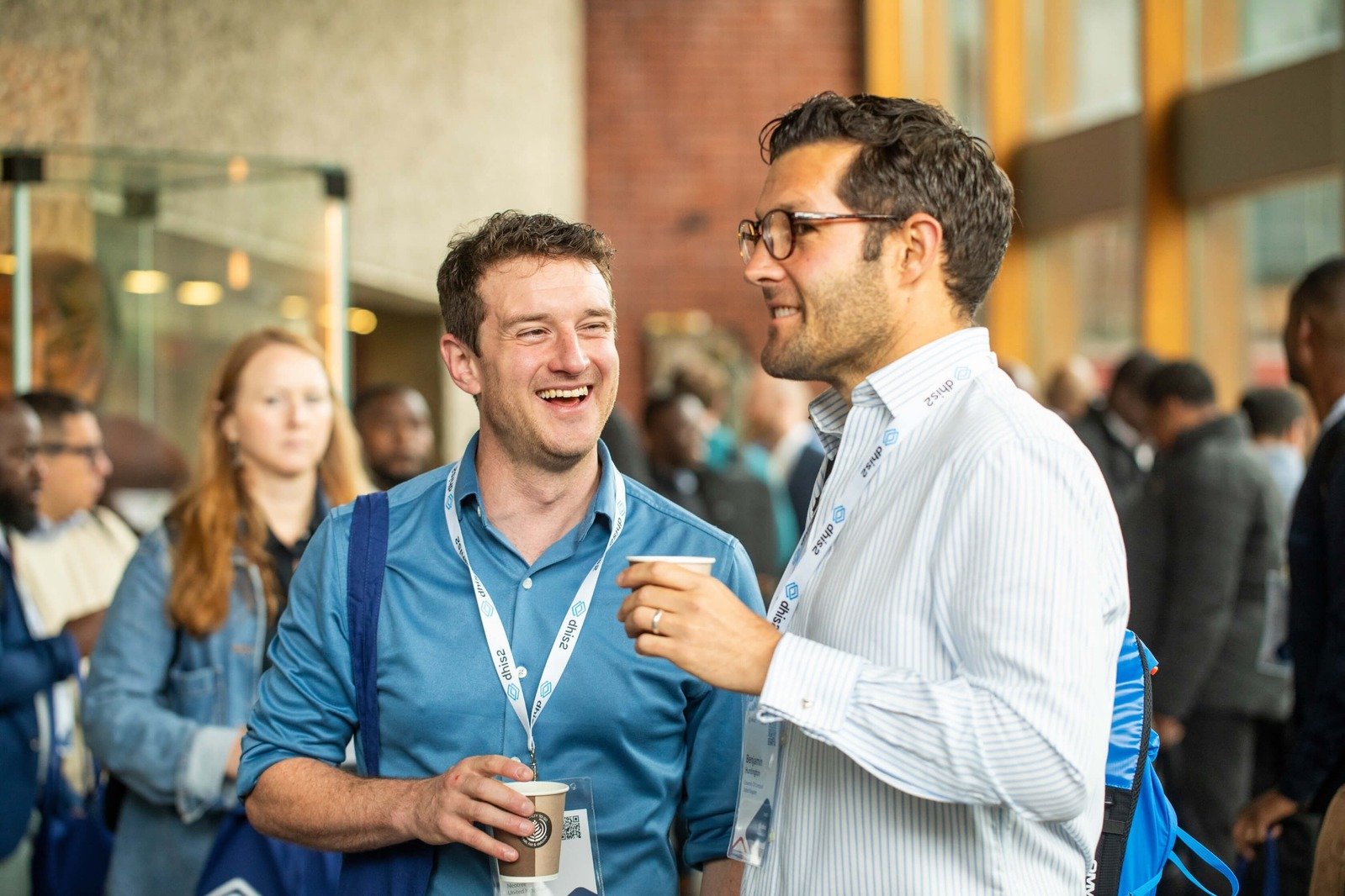 Two male attendees networking and laughing during a coffee break at the DHIS2 Annual Conference.